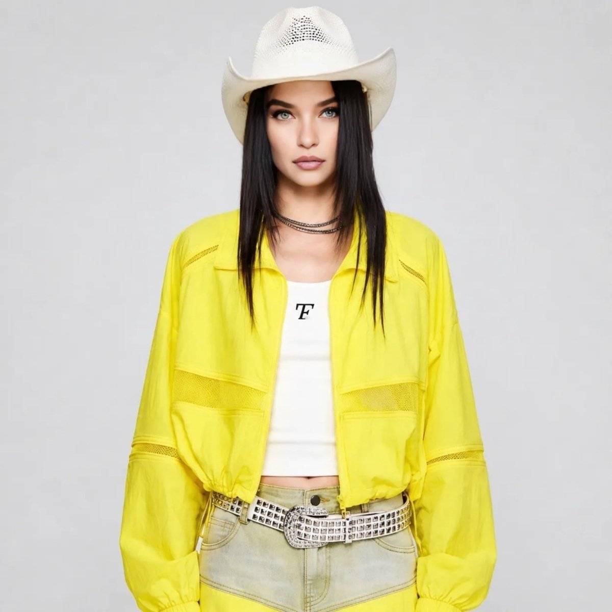 Woman wearing Kouvr yellow cropped lightweight windbreaker jacket with sheer mesh panels and western hat.