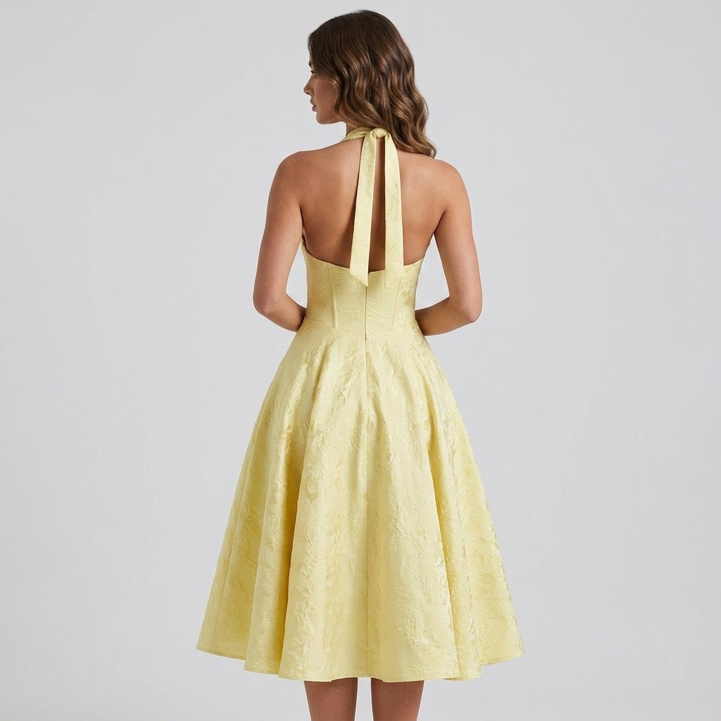 Back view of a model wearing the Kouvr yellow open back halter midi dress showcasing the fitted corset waist and textured fabric.