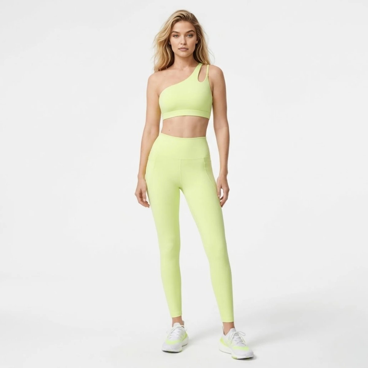 Front view of blonde model wearing Kouvr yellow one shoulder sports bra and high waisted leggings activewear set