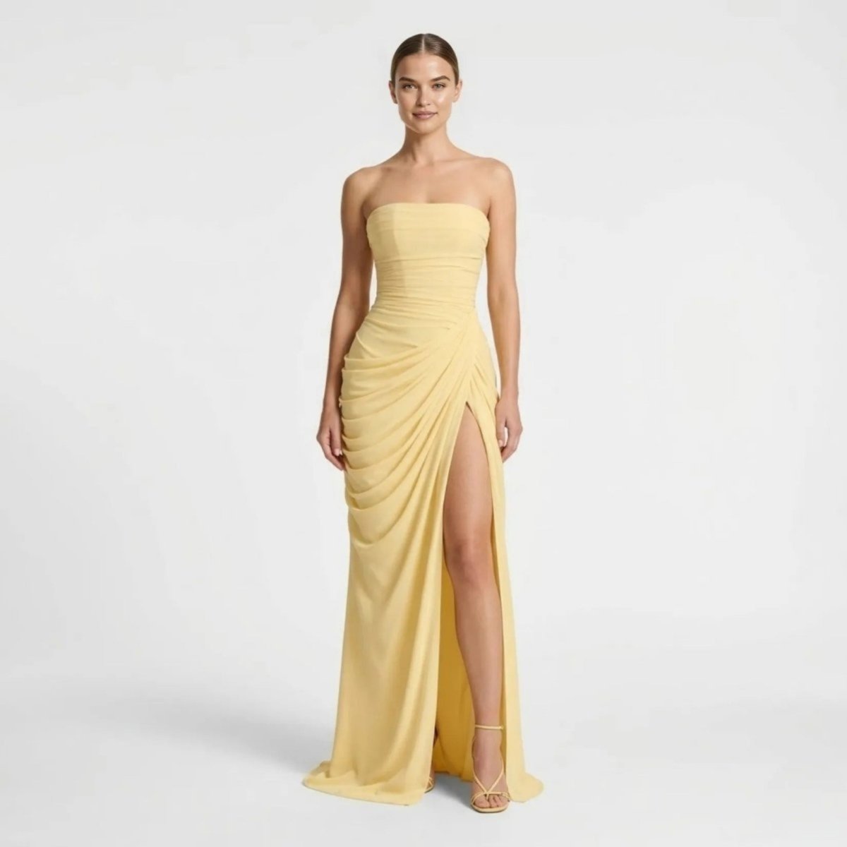 Elegant woman wearing Kouvr yellow strapless ruched maxi dress with high thigh slit looking forward.